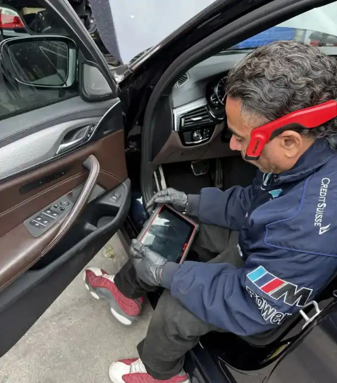 Favio, lead mechanic at Beacon Auto Care San Mateo, in the driver door of a BMW M550i (G30 N63 V8) running an Autel diagnostic scan mid-pull