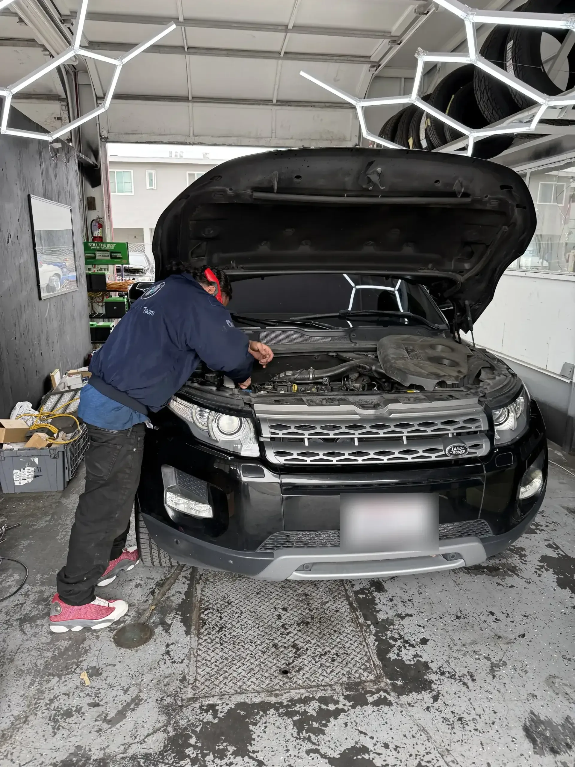 Favio, lead mechanic at Beacon Auto Care San Mateo, leaning into the engine bay of a Range Rover Evoque
