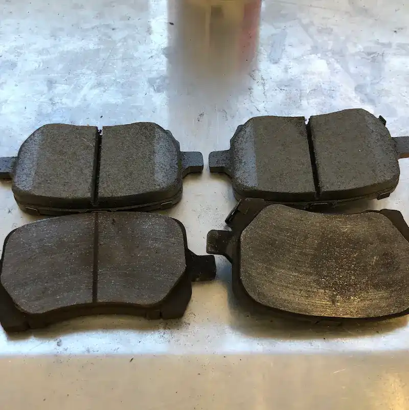 Worn brake pads next to new brake pads showing material loss — San Mateo brake repair